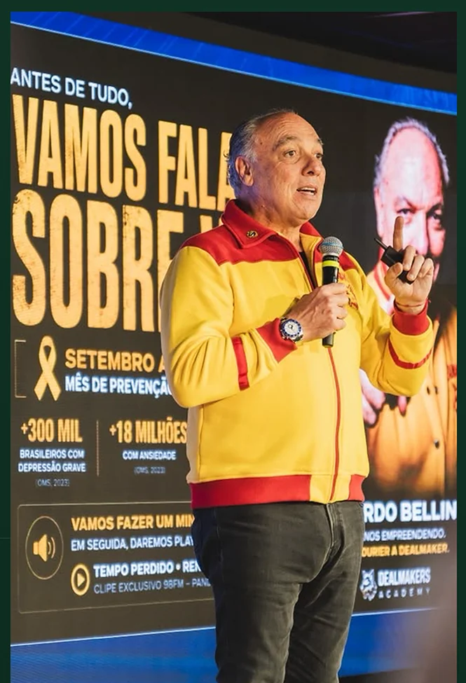 Ricardo Bellino no palco, com microfone e a jaqueta Dealmakers